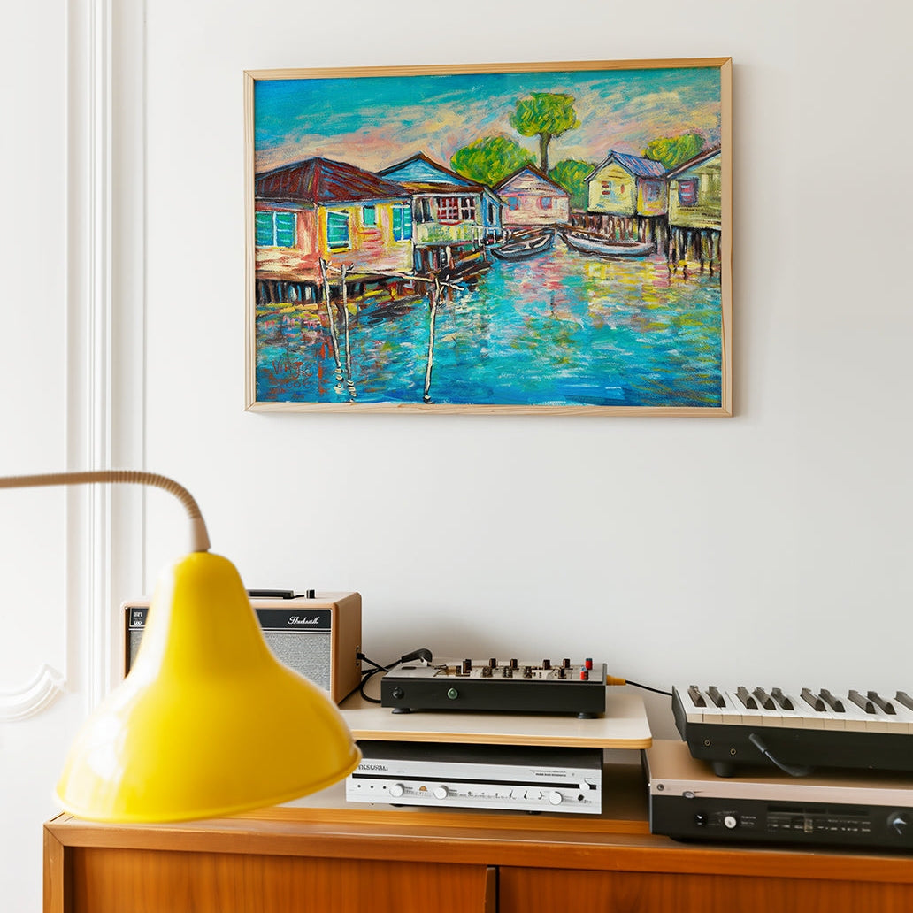 Framed painting of a waterfront scene above a wooden cabinet with electronic equipment.