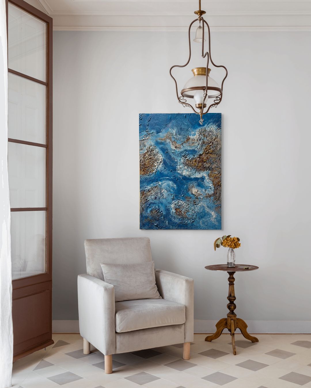 Living room with a beige armchair, abstract blue painting, and wooden side table.