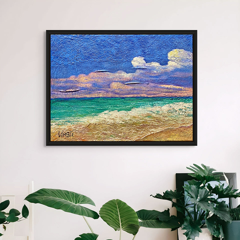 Framed artwork of a beach scene above a plant in a room with white walls and wooden floor.