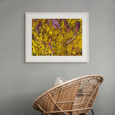 Wicker chair in front of a framed abstract artwork on a gray wall.
