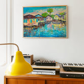 Framed painting of a waterfront scene above a wooden cabinet with electronic equipment.