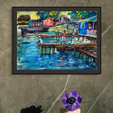 Framed painting of a colorful dock scene on a gray wall with a purple flower on a stand.