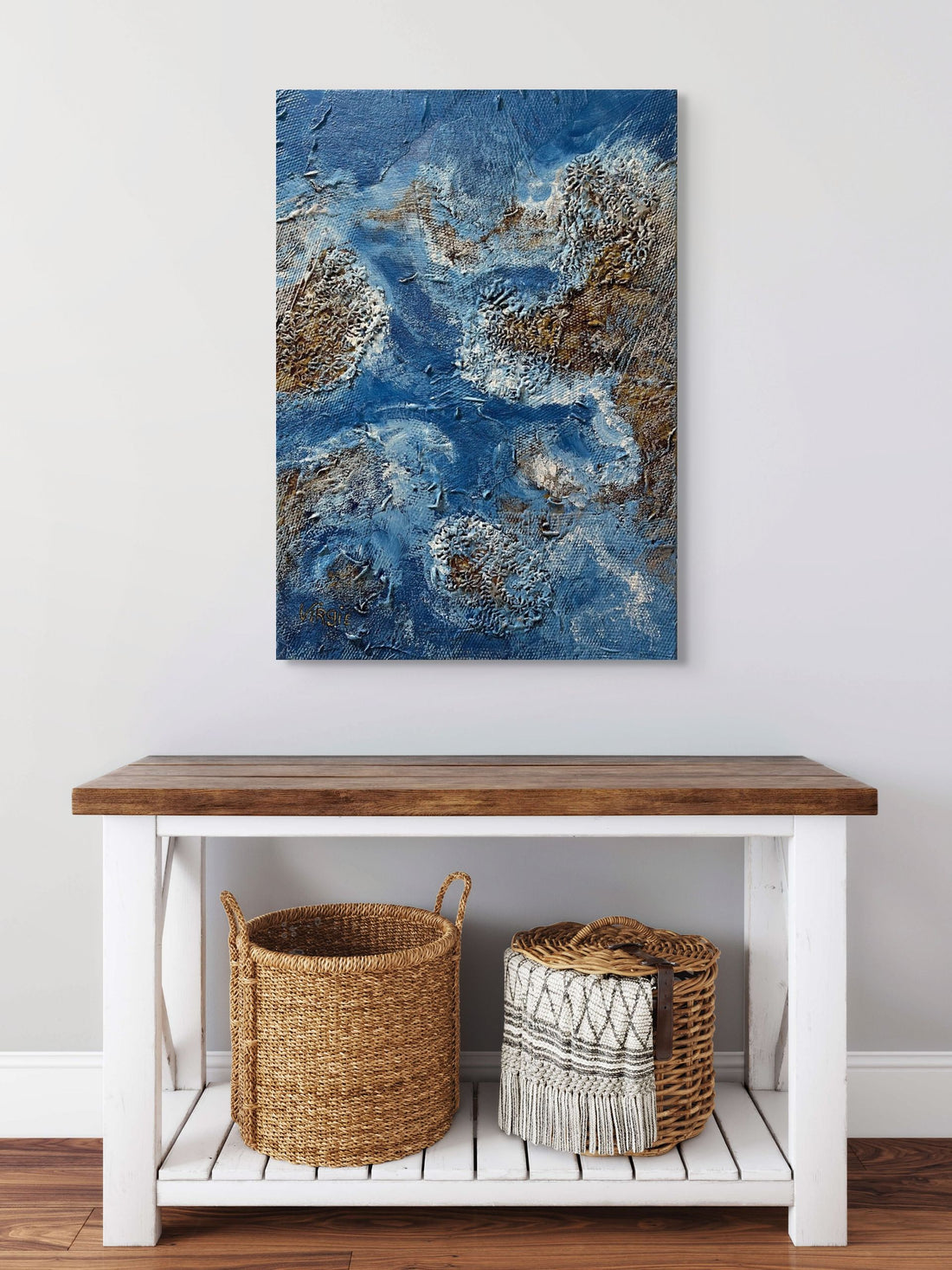 Abstract blue and brown painting above a wooden table with wicker baskets.